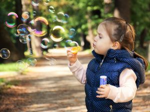 little girl blowing bubble outdoors