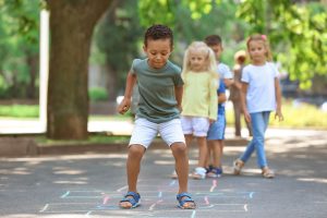 Preschool children playing hopscotch outdoors