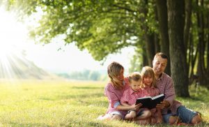 A young family reading in nature